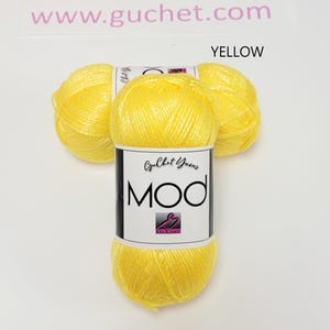 May include: Three skeins of bright yellow yarn arranged in a cluster. Each skein features a white paper label with the text Guchet Yarns MOD and a small logo. The text www.guchet.com is visible at the top, and the word YELLOW is printed above.