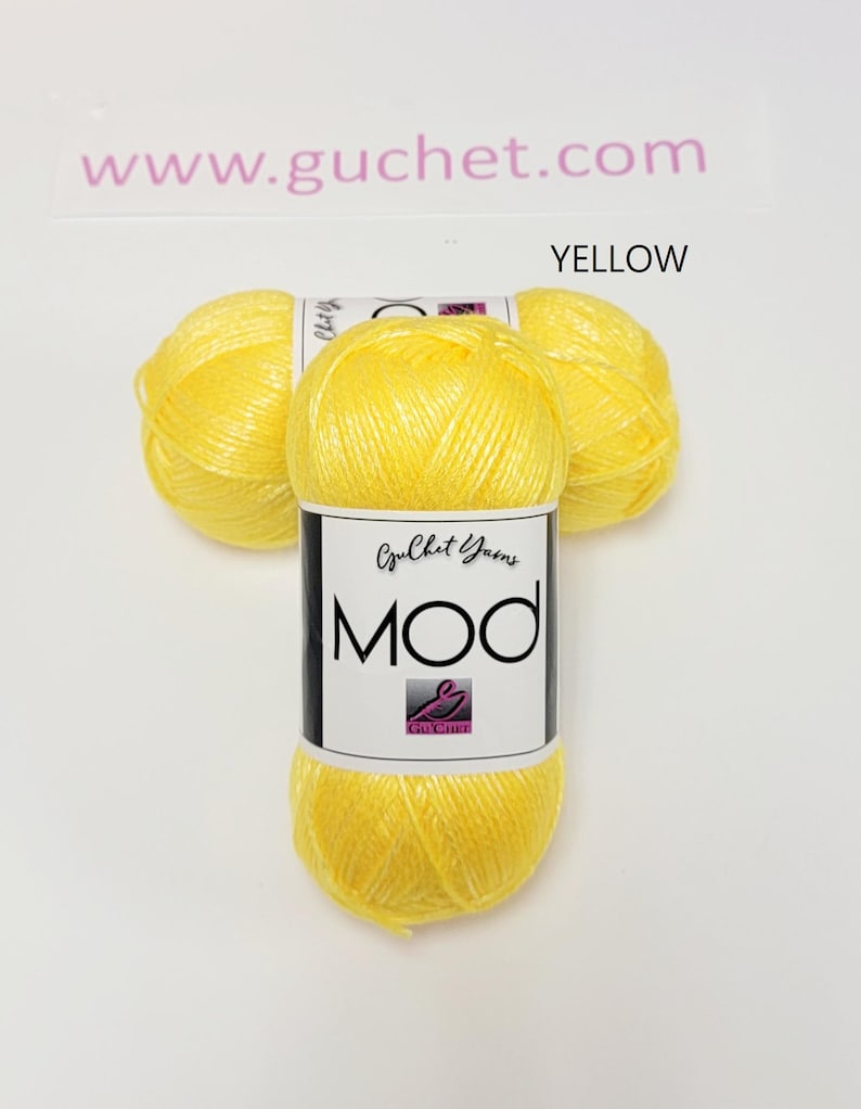 May include: Three skeins of bright yellow yarn arranged in a cluster. Each skein features a white paper label with the text Guchet Yarns MOD and a small logo. The text www.guchet.com is visible at the top, and the word YELLOW is printed above.