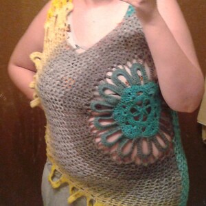 May include: A crocheted vest with a large, teal and gray flower design. The vest is made with a variety of colors, including yellow, gray, and teal.