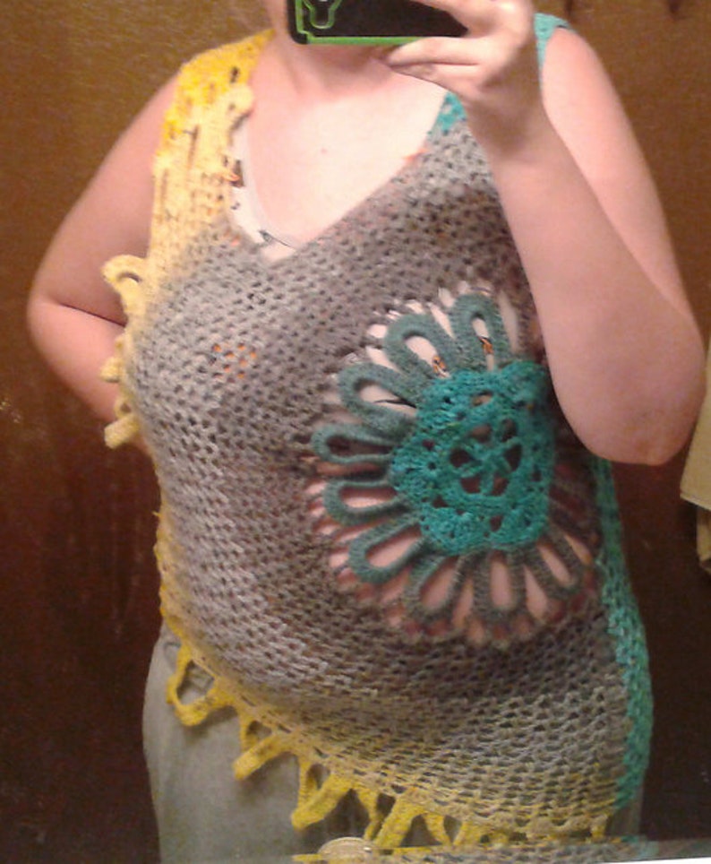 May include: A crocheted vest with a large, teal and gray flower design. The vest is made with a variety of colors, including yellow, gray, and teal.