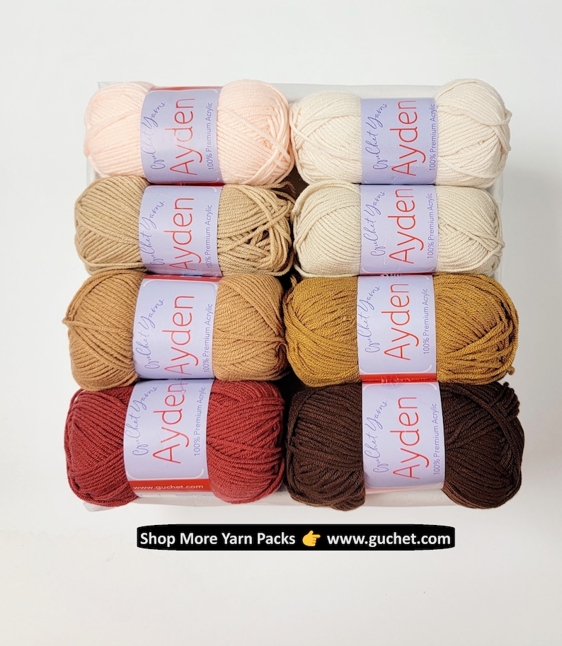 Op de afbeelding: Een verzameling garenbollen in verschillende kleuren, waaronder perzik, cr&egrave;me, beige en bruin. Elke bol heeft een label met "Ayden" en "100% Premium Acrylic". De tekst "Shop More Yarn Packs www.guchet.com" is ook zichtbaar.