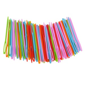May include: A large bundle of colourful plastic needles, arranged in a fan shape. The needles are in various shades of pink, orange, red, green, blue, and yellow.