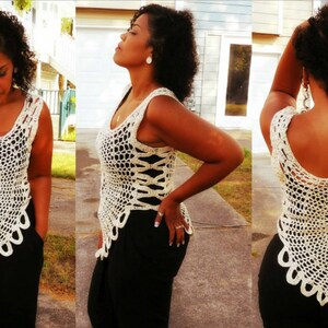 May include: A white crochet top with a scalloped hem and a floral design. The top is sleeveless and has a loose fit.