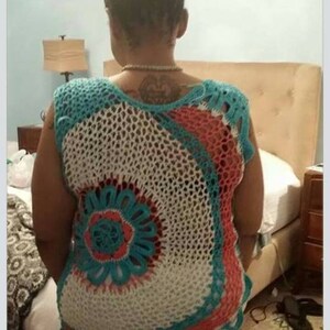 May include: A crocheted top with a white, turquoise, and coral design. The top is sleeveless and has a loose fit.
