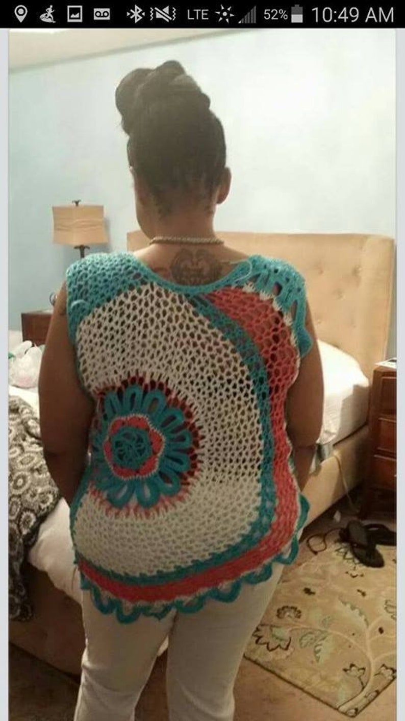 May include: A crocheted top with a white, turquoise, and coral design. The top is sleeveless and has a loose fit.