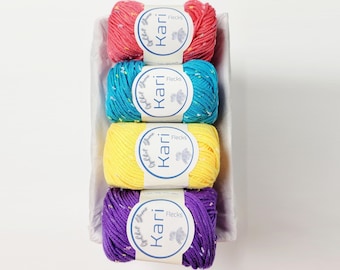 May include: Four balls of yarn in a white basket. The yarn is in the colors pink, blue, yellow, and purple. Each ball has a label that says "Kari Flecks" on it.