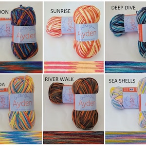 Op de afbeelding: Zes bollen Ayden-garen in diverse kleurencombinaties. Elke bol heeft een label met de merknaam en "100% Premium Acrylic". De kleurstijlen zijn gelabeld met "Blue Lagoon", "Sunrise", "Deep Dive", "Pina Colada", "River Walk" en "Sea Shells".