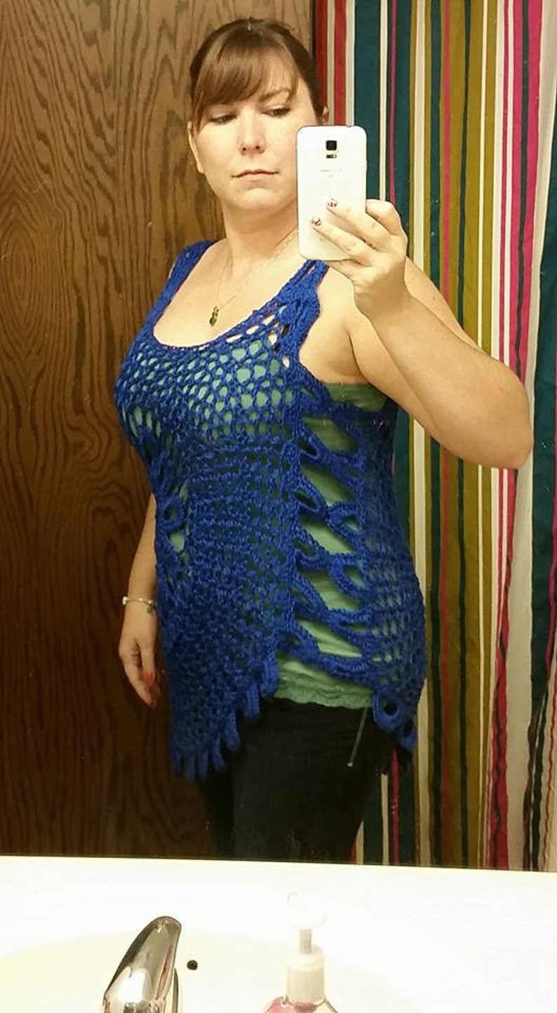 May include: A blue crocheted top with a loose, open weave. The top has a scoop neck and a sleeveless design. The top is worn over a green tank top.