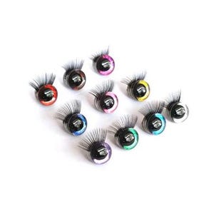 May include: Assortment of ten colorful plastic eyes with black pupils and eyelashes. The eyes are various colors including red, pink, purple, blue, green, yellow, and black.