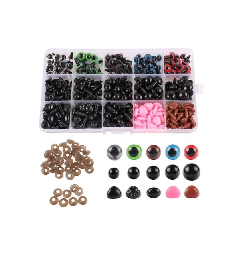 May include: A clear plastic storage box filled with various sizes and colors of plastic safety eyes for crafts. The box has 12 compartments, each filled with a different color or size of eyes. There are also loose safety eyes and washers in the image.