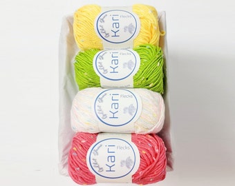 May include: A rectangular basket holds four skeins of Kari Flecks yarn in yellow, green, white, and pink. Each skein has a label with the brand name and the word "Flecks". The yarn is speckled with various colors.
