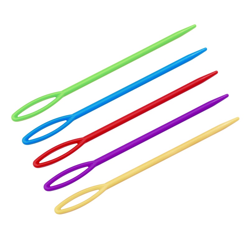 May include: Five plastic yarn needles in different colours: green, blue, red, purple, and yellow. The needles have a loop at one end for threading yarn.