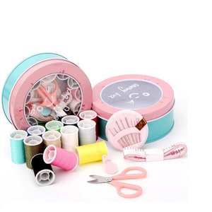 May include: A pink and blue sewing kit with a variety of colorful threads, needles, scissors, and a tape measure. The kit is in a round tin with a smiling face and the words "Sew Happy" on it.
