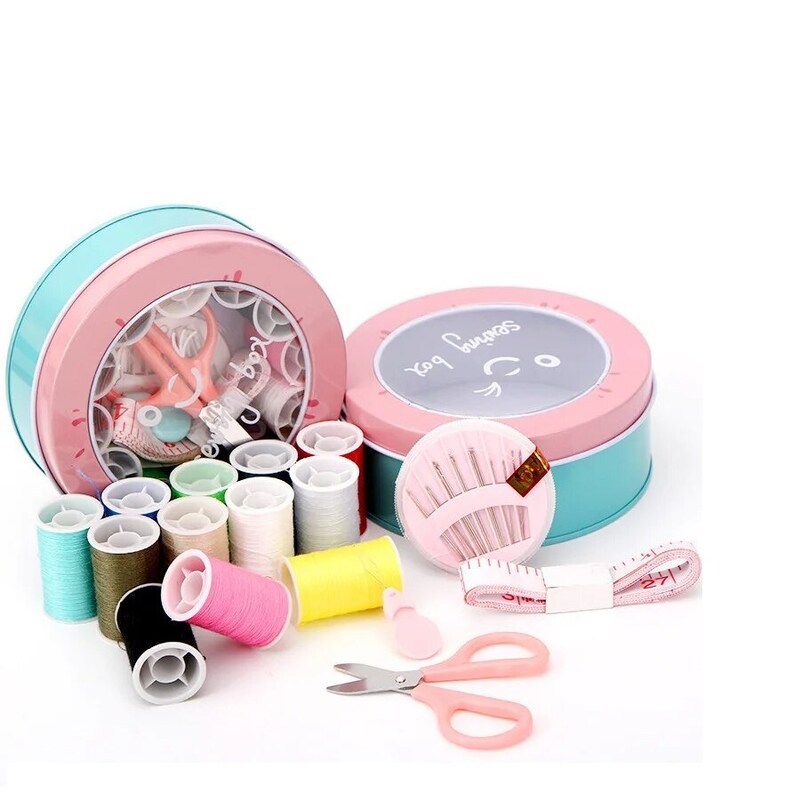 May include: A pink and blue sewing kit with a variety of colorful threads, needles, scissors, and a tape measure. The kit is in a round tin with a smiling face and the words "Sew Happy" on it.