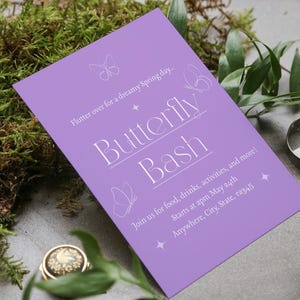 Op de afbeelding: Een paarse uitnodigingskaart met witte tekst die luidt: "Flutter over for a dreamy Spring day. Butterfly Bash Join us for food, drinks, activities, and more! Starts at 2pm May 24th Anywhere, City, State, 12345". De kaart heeft een vlinderontwerp.
