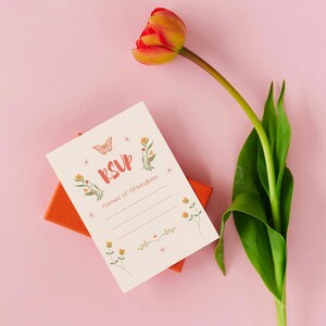 Spring Bloom Bar invitation with pastel florals and butterfly design. Perfect for printable brunch party invites or bouquet-making events. Styled on a pink background with an orange gift box and greenery.