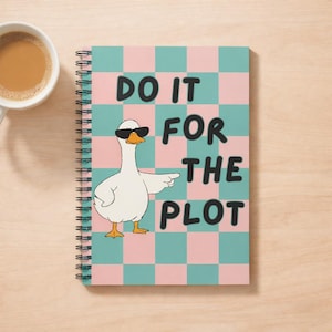 May include: Spiral-bound notebook with a teal and pink checkered pattern. The cover features a cartoon goose wearing sunglasses and pointing, with the text "DO IT FOR THE PLOT" in black letters. A cup of coffee sits to the left.
