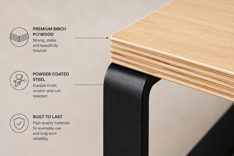 May include: A table corner featuring a light-colored birch plywood top with visible layered edges and a matte black powder-coated steel leg. Text labels highlight premium birch plywood, powder-coated steel, and built-to-last construction.