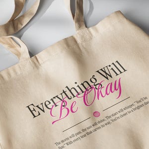 May include: A beige canvas tote bag with black and pink text that reads "Everything Will Be Okay". The text is accompanied by a quote: "The storm will pass, the sun will shine, The stars will whisper, "You'll be fine." With every tear that carves its way, You're closer to a brighter day."