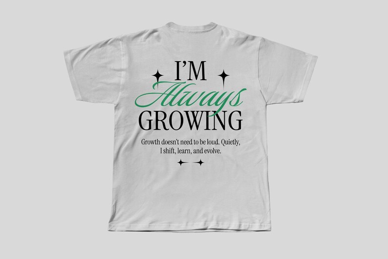 May include: White t-shirt with a green and black graphic that says "I'm Always Growing". The graphic also includes the text "Growth doesn't need to be loud. Quietly, I shift, learn, and evolve."