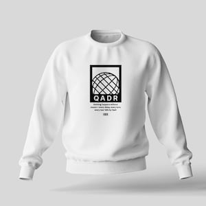 May include: White sweatshirt with a black graphic of a globe and the text "QADR" and the phrase "Nothing happens without reason, every day is a new turn, every year falls by Qadr".