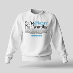May include: White crewneck sweatshirt with the text "You're Stronger Than Yesterday" printed in black with blue accents. The text is surrounded by a small paragraph of text.