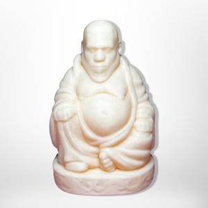 May include: A cream-coloured Buddha statue in a seated position. The figure has a large belly and is wearing a robe. The statue is on a round base and has a serene expression. The statue is made of a solid material.
