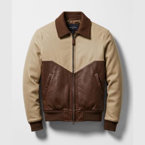 Op de afbeelding: Een tweekleurige leren jas in beige en bruin. De jas heeft een bruine kraag, een ritssluiting en geribde manchetten en zoom. Het ontwerp bevat een chevronpatroon aan de voorkant. Een klassiek kledingstuk.
