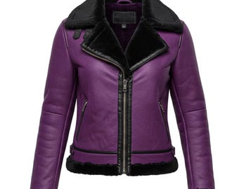 May include: A purple aviator jacket with a black faux fur collar and lining. The jacket features a front zipper closure, two side pockets, and black trim along the cuffs and hem. The jacket is made of a smooth, leather-like material.