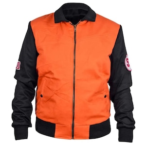 Puede incluir: Chaqueta bomber naranja y negra con cuello y puños negros. La chaqueta tiene una cremallera de largo completo y dos bolsillos pequeños. Parches con el número 5 y una letra en las mangas.