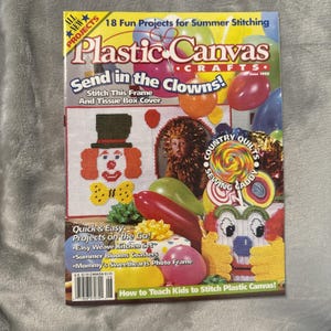 Op de afbeelding: Een uitgave van het tijdschrift Plastic Canvas Crafts uit juni 1995 met 18 leuke projecten voor zomerse handwerken. De cover toont kleurrijke ballonnen, een fotolijst van plastic canvas in clownsthema, een tissuebox en een speldenkussen.