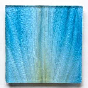 May include: A square glass tile featuring a vibrant blue gradient pattern that radiates from the center. The design displays delicate, fine vertical lines resembling natural petal textures, transitioning from a pale yellow-green core to deep blue edges.