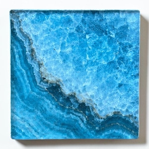 May include: A square tile featuring a vibrant blue crystalline pattern with deep navy and turquoise veining. The surface displays a textured, translucent appearance with layered mineral formations that create a natural, organic gradient across the piece.