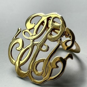 Puede incluir: Anillo con monograma dorado con las letras entrelazadas "JFF" en escritura cursiva. El anillo tiene un acabado pulido y un diseño clásico y elegante, adecuado para el uso diario o ocasiones especiales.