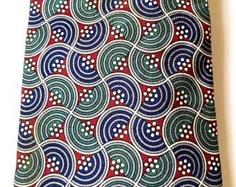 May include: A red, blue, and green patterned tie with a repeating geometric design of circles and semi-circles.