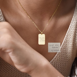 Könnte beinhalten: Eine goldfarbene rechteckige Anhänger-Halskette mit der Aufschrift "Love you forever! ♡ mom". Der Anhänger hängt an einer filigranen Kette. Die Halskette wird um den Hals getragen.