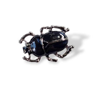 May include: A black beetle-shaped brooch with silver-colored legs and antennae. The brooch has a glossy, dark surface and is set against a white background. This insect-themed accessory is suitable for jackets, bags, or hats.