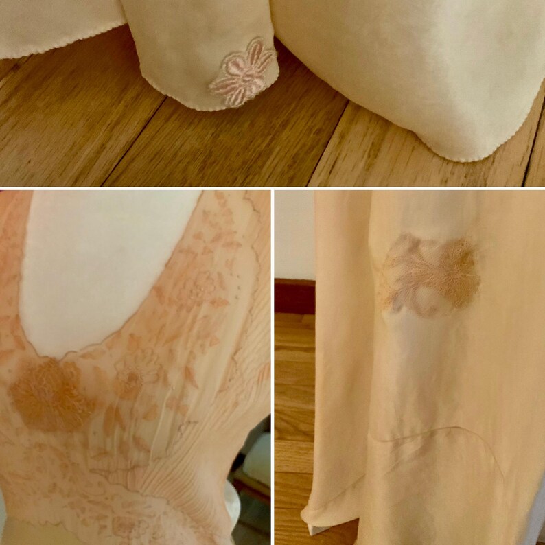 May include: Close-up of a cream-colored garment with delicate floral embroidery in shades of pink. The fabric appears soft and flowing, with subtle textures and details. The garment's design includes a V-neckline and a flowing skirt.