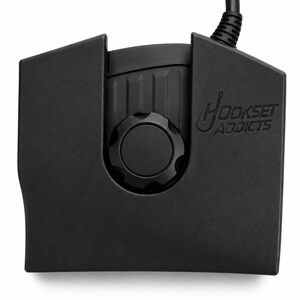 May include: A black electronic control unit featuring a central circular dial and a top-mounted cable. The device has a matte finish and displays the embossed text "HOOKSET ADDICTS" on the right side, with a grooved section above the dial.