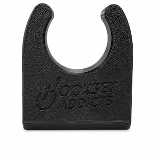 Peut inclure: Un clip en plastique noir en forme de U avec une surface texturée. L'avant du clip présente le texte en relief Hookset Addicts, avec la lettre H stylisée comme un hameçon. Le clip possède une large ouverture circulaire sur le dessus.