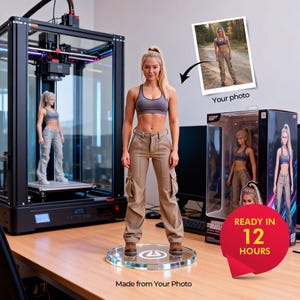 May include: A 3D-printed figurine of a woman in athletic wear stands on a clear circular base. The figurine is next to a 3D printer and a box with a similar figurine. The image includes the text "Made from Your Photo" and "Ready in 12 Hours."
