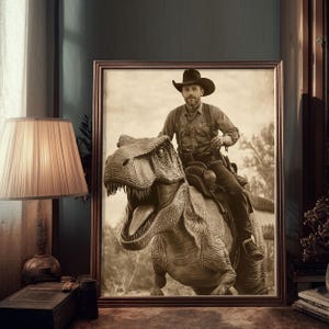 Op de afbeelding: Sepia-getinte ingelijste prent met een cowboy die op een Tyrannosaurus Rex rijdt. De cowboy draagt een hoed, een overhemd en een broek en zit op een zadel. De dinosaurus heeft zijn mond open. De prent wordt aan een muur naast een lamp getoond.