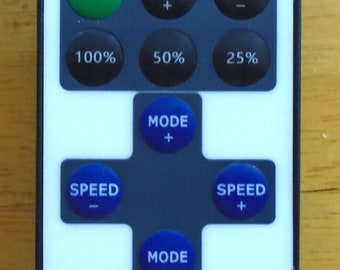 Può includere: Telecomando wireless RF bianco con pulsante di accensione, comandi luce, luminosità, velocità e modalità. Dispone di pulsanti per i livelli di luminosità 100%, 50% e 25%. Il telecomando ha una forma rettangolare arrotondata.