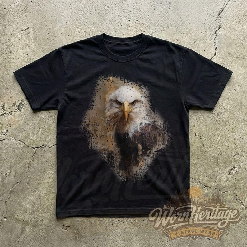 May include: Black t-shirt featuring a detailed graphic of a bald eagle's head and chest. The eagle is depicted with white feathers, a yellow beak, and a stern expression. The shirt has a vintage wear logo at the bottom.