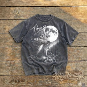 Op de afbeelding: Donkergrijs t-shirt met een gedetailleerde illustratie van een wolf en een volle maan op de achtergrond. Een tweede wolf huilt. Het shirt heeft de tekst "Worn Heritage Vintage Wear".