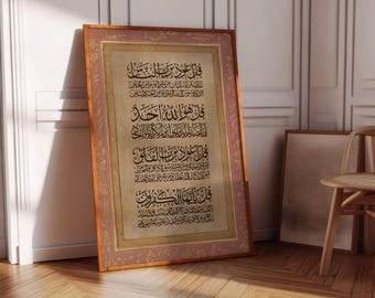 May include: A framed artwork featuring Arabic calligraphy in black ink on a beige background. The frame is a warm brown with a pink border. The artwork is leaning against a white wall, with a wooden floor in the foreground.