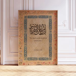 May include: A framed print featuring Arabic calligraphy in black ink on a parchment-toned background. The frame has a decorative border with floral and geometric patterns in shades of gold, blue, and red. The text reads, "So, surely with hardship comes ease."