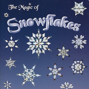May include: The Magic of Snowflakes book cover featuring 17 snowflake designs by Deverick Wood. The cover is a dark blue with white snowflakes of various sizes and designs.