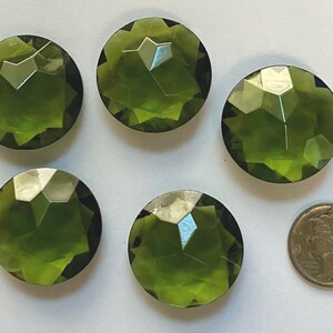 May include: Five faceted, olive-green glass cabochons are displayed next to a silver coin. The cabochons are round with multiple facets, reflecting light. The coin is a silver Mercury dime.