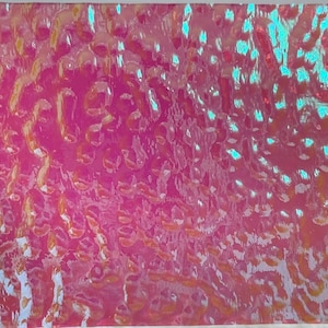 May include: A sheet of iridescent holographic vinyl with a textured, bubble-like pattern. The vinyl is pink, blue, and gold.